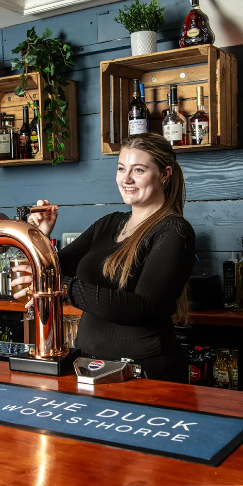 A smiling member of the team behind the bar at The Duck