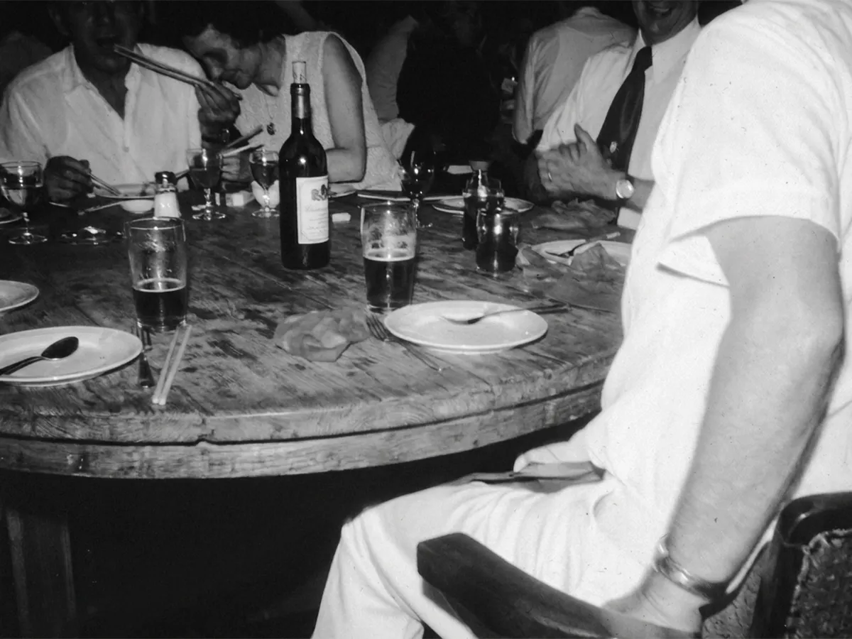 Black and white photograph of locals sharing drinks around a pub table